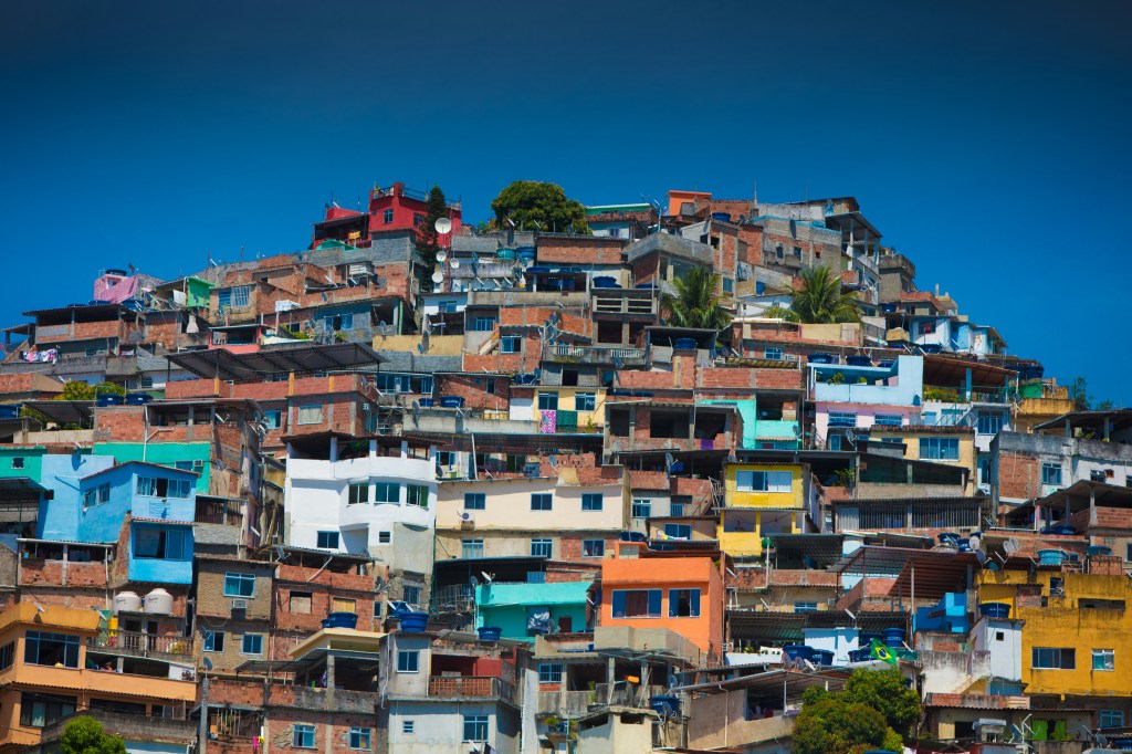 A vibrant hillside community featuring a densely packed arrangement of colorful houses and buildings under a blue sky.